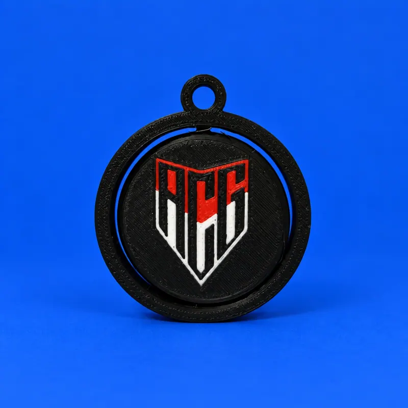 Chaveiro giratório do Atlético Goianiense com aro e elo pretos e monograma ACG vermelho e branco, apoiado sobre fundo azul