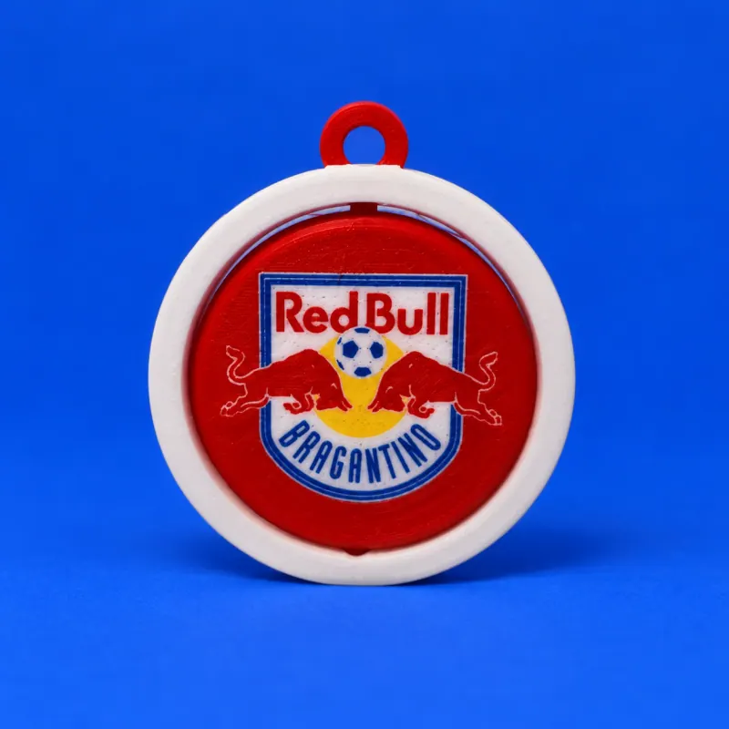 Chaveiro giratório do Red Bull Bragantino com aro branco, elo e disco vermelhos, escudo multicolor com dois touros e bola, textura de filamento e fundo azul