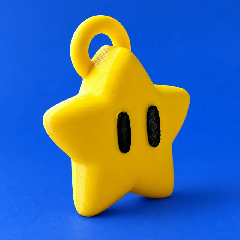 Estrela amarela de cinco pontas com dois olhos pretos impressos e elo superior amarelo integrado, apoiada sobre fundo azul
