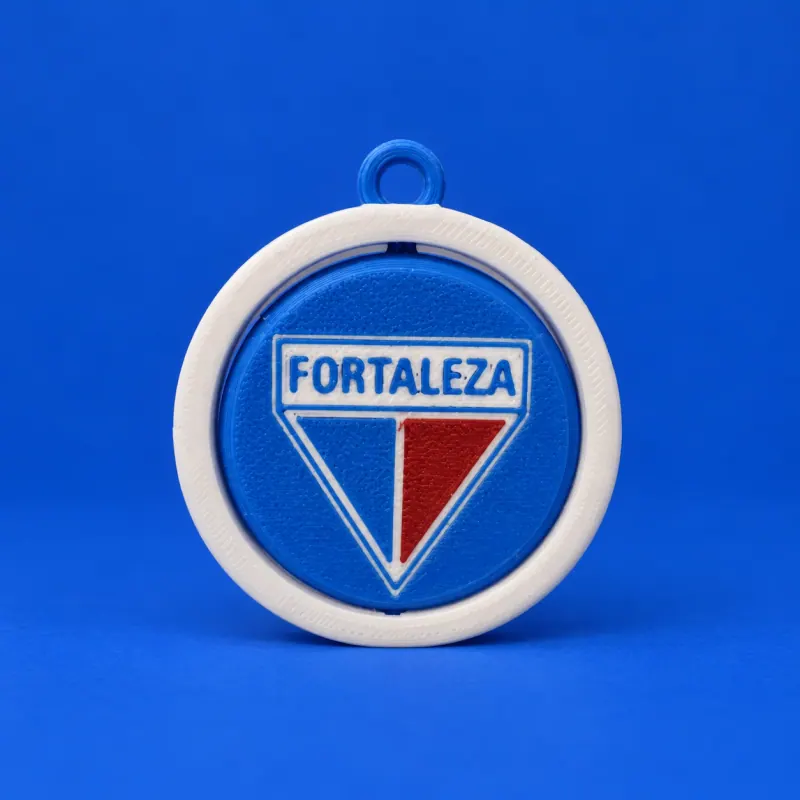 Chaveiro giratório do Fortaleza com aro branco, elo azul, disco azul e escudo triangular azul vermelho e branco, apoiado sobre fundo azul