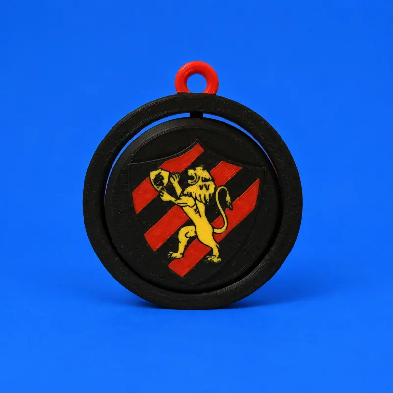 Chaveiro giratório do Sport com aro preto, elo vermelho e leão amarelo sobre escudo rubro-negro, textura impressa aparente e fundo azul